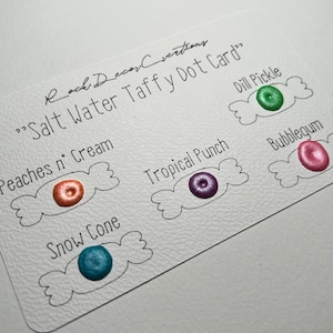 May include: A white card with the text "Salt Water Taffy Dot Card" and the maker's name. The card features six colourful dots labelled with candy flavours like "Peaches n' Cream" and "Bubblegum".