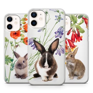 May include: Three clear phone cases featuring floral designs and bunny illustrations. The cases depict a black and white bunny, a brown bunny, and a variety of flowers in shades of red, pink, blue, and yellow.