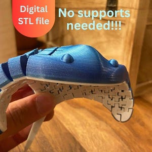May include: A 3D-printed articulated object in blue and white, held in a hand. The object has a segmented design with a curved shape. Text in the image reads "Digital STL file" and "No supports needed!!!".