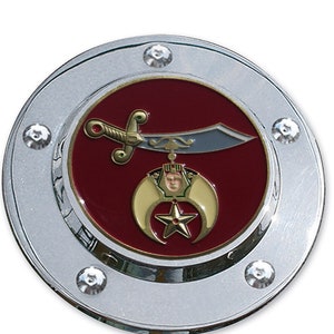 May include: A silver-colored round emblem with a red background and a gold crescent moon and star design. A gold sword with a silver blade is hanging from the crescent moon.