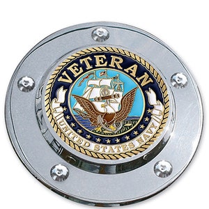 May include: A silver round car emblem with a gold and blue United States Navy Veteran seal. The seal features an eagle, a ship, and the words "United States Navy" and "Veteran".