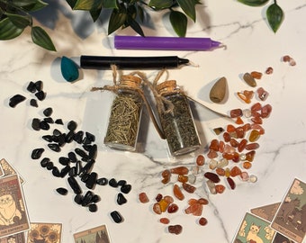 May include: A collection of spiritual items, including tarot cards, candles, crystals, and herbs. The tarot cards feature cat illustrations. The crystals are black and orange. Two small glass jars are filled with herbs. A purple and black candle are also present.