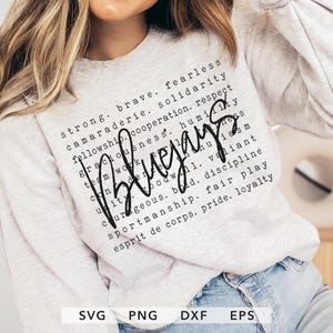 Puede incluir: Una sudadera gris claro con la palabra "Blugays" en cursiva. El diseño incluye una lista de palabras como "fuerte", "valiente" y "intrépido" en una fuente de bloque. La parte inferior de la imagen muestra los tipos de archivo: SVG, PNG, DXF y EPS.