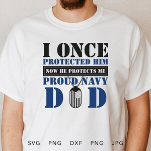 May include: White t-shirt with black text that reads "I once protected him now he protects me proud navy DOD". The text is surrounded by a blue outline. A blue and white dog tag is in the centre of the text.