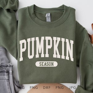 May include: A green sweatshirt with the text "PUMPKIN SEASON" in white lettering. The sweatshirt is laid flat on a white surface.