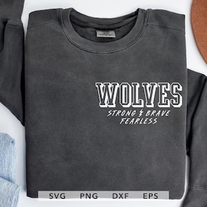 May include: A dark gray sweatshirt with the word "WOLVES" in white block letters. Below the word are the words "STRONG BRAVE FEARLESS" in a script font. The sweatshirt has long sleeves and a crew neck.
