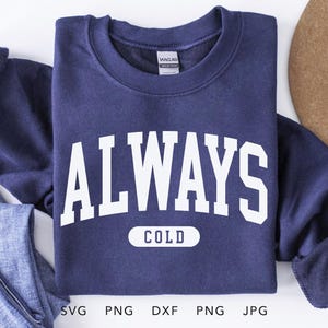 May include: A navy blue sweatshirt with white text that reads "ALWAYS COLD". The text is in a collegiate font style.