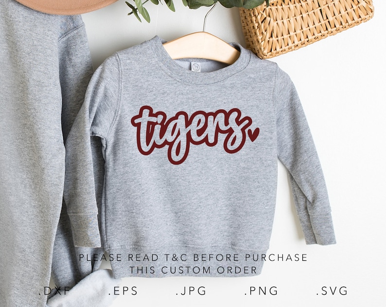 May include: Gray sweatshirt with a maroon "tigers" design and a small heart. The text "PLEASE READ T&C BEFORE PURCHASE THIS CUSTOM ORDER" is printed below the design. The sweatshirt is on a hanger.