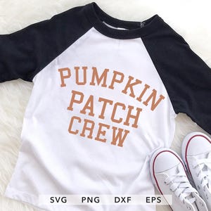 Peut inclure: Un t-shirt de style raglan blanc et noir avec le texte "PUMPKIN PATCH CREW" en lettres orange. Des baskets blanches avec des bordures rouges sont en bas. Le t-shirt est probablement pour enfants.