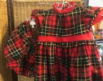 Könnte beinhalten: Ein rot-grün-schwarzes kariertes Kleid mit rotem Kragen und einem roten Band um die Taille. Das Kleid hat kurze Ärmel und einen vollen Rock.