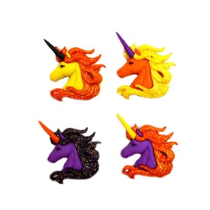 May include: Four colourful unicorn head decorations. Each unicorn has a horn and mane in different colours, including yellow, orange, purple, and black. The manes have glitter accents. The unicorns are set against a white background.