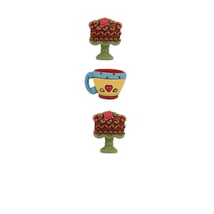 Op de afbeelding: Drie kleurrijke knopen met een chocoladetaart met een roze roos erop, een gele theekop met blauwe en rode accenten en nog een chocoladetaart met een roze roos erop.