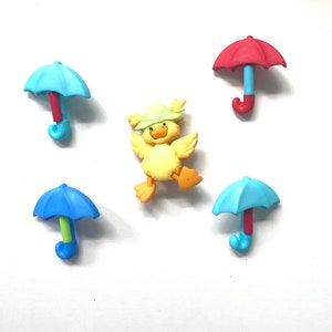 May include: A collection of colorful buttons featuring a yellow duck wearing a green hat and four miniature umbrellas. The umbrellas have blue and red canopies with matching handles. The duck is in a playful pose.