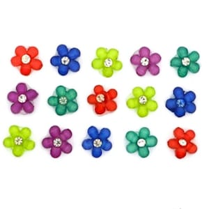 Op de afbeelding: Assortiment van 15 kleurrijke bloemvormige versieringen met strasssteentjes in het midden. De bloemen zijn in tinten rood, paars, blauw, groen en geel.