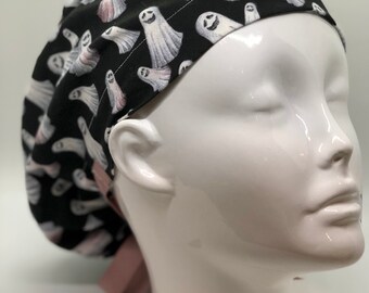 Könnte beinhalten: Eine schwarze OP-Mütze mit einem weißen Geistermuster und einer rosafarbenen Schleife. Die Mütze wird auf einem weißen Mannequin-Kopf getragen.