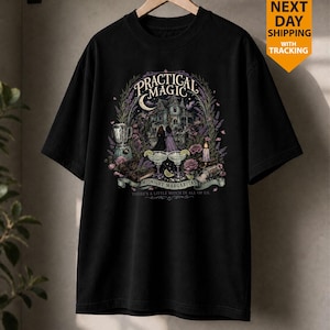 May include: A black short-sleeved t-shirt featuring a graphic print of a house, two figures, a blender, margaritas, and flowers. The text reads Practical Magic, Midnight Margaritas, and There's a little witch in all of us, surrounded by botanical elements.