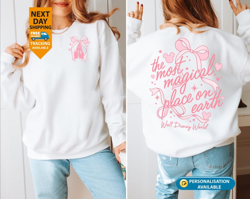 May include: White sweatshirt with a pink castle and bow design on the front. The back features the text "the most magical place on earth" with a bow and heart accents. Walt Disney World is printed below.