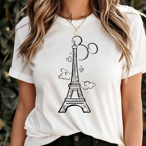 K&ouml;nnte beinhalten: Wei&szlig;es T-Shirt mit einer schwarzen Strichzeichnung des Eiffelturms, drei Kreisen, Wolken und Herzen. Das Design ist zentriert. Das T-Shirt hat kurze &Auml;rmel und bietet einen l&auml;ssigen Stil. Das Design ist einfach und stilvoll.
