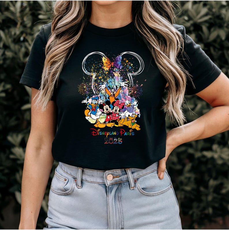 May include: Black t-shirt with a colorful graphic of Mickey Mouse and friends in front of the Disneyland Paris castle. The graphic includes fireworks and a butterfly. The text "Disneyland Paris 2025" is printed below the graphic.