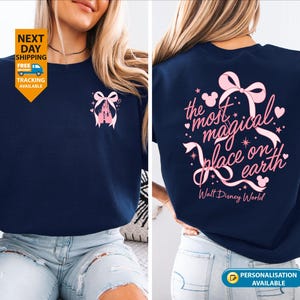 May include: Navy blue t-shirt with a pink castle and bow design on the front. The back of the shirt features the text "the most magical place on earth" with a bow and stars. Walt Disney World is printed below.