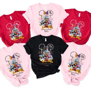 May include: Six pink, red, and black t-shirts with a Mickey Mouse design and the text "Disneyland Paris 2023". The shirts have different names on them, including "Mom", "Dad", "Grandma", "Grandpa", and "Sis".