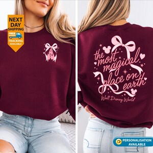 May include: Burgundy sweatshirt with a pink castle and bow design on the front. The back features the text "the most magical place on earth" with a bow, hearts, and Mickey Mouse silhouettes. "Walt Disney World" is printed below.