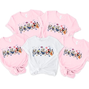 Pu&ograve; includere: Cinque magliette a maniche corte rosa e bianche. Ogni maglietta presenta una grafica a cartoni animati dei personaggi Disney in abbigliamento nautico, tra cui Topolino e Minnie, Paperino e Pippo, con ancore e un timone.