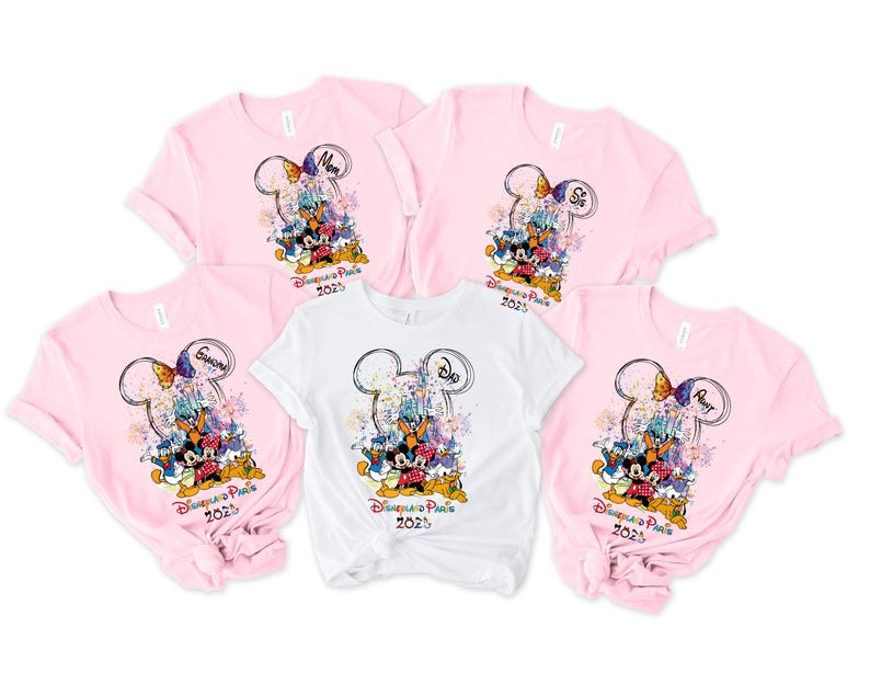 May include: Five pink and white t-shirts with a Mickey Mouse and Minnie Mouse design. The shirts have the text "Disneyland Paris 2023" and the words "Mom", "Sis", "Auntie", and "Grandma".