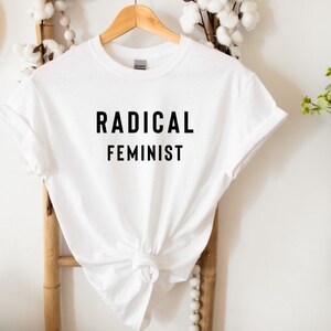 May include: White t-shirt with black text that reads "RADICAL FEMINIST".