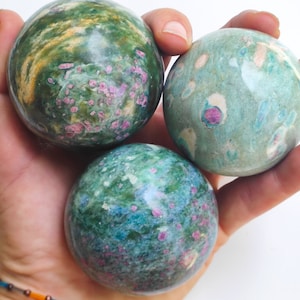 Peut inclure: Trois sphères de pierres précieuses vertes, bleues et roses avec un motif marbré. Les sphères sont lisses et polies.