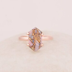 May include: A rose gold ring featuring a pink and gold gemstone. The gemstone is uniquely shaped with an irregular geometric design.