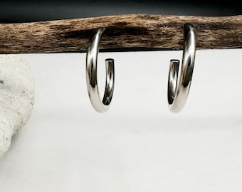 May include: A pair of silver hoop earrings. The earrings are simple and elegant, with a smooth, polished finish.