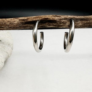 May include: A pair of silver hoop earrings. The earrings are simple and elegant, with a smooth, polished finish.
