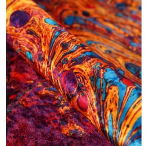 Peut inclure: Gros plan sur un tissu avec un motif abstrait tourbillonnant dans des tons d'orange, de rouge, de bleu et de violet.