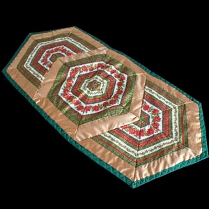 Könnte beinhalten: Ein grüner und goldener Tischläufer mit einem geometrischen Muster aus roten Weihnachtssternen. Der Läufer ist aus Stoff und hat eine gesteppte Textur.