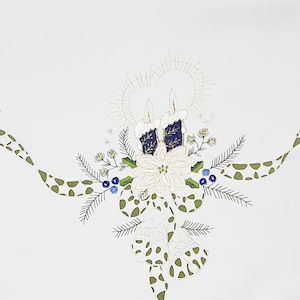 Peut inclure: Nappe blanche avec broderie de Noël. Elle présente deux bougies avec des accents bleus et dorés, un poinsettia et un ruban vert à pois. Le motif est entouré de brins de verdure et de petites baies bleues.