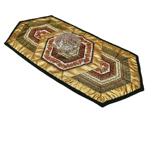 Könnte beinhalten: Ein goldfarbener und grüner gesteppter Tischläufer mit sechseckigem Muster und einer klaren Glasschüssel in der Mitte.