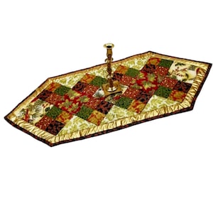 Könnte beinhalten: Ein goldfarbener und roter Patchwork-Tischläufer mit goldfarbenem Satinbesatz und einem goldenen Kerzenständer in der Mitte.