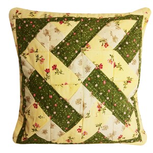 Peut inclure: Un oreiller patchwork jaune et vert avec un motif floral. L'oreiller est composé de carrés de tissu cousus ensemble en diagonale.