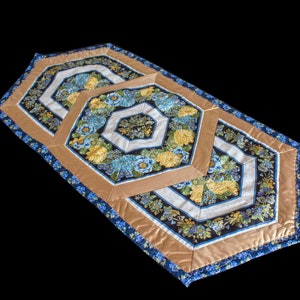 May include: A table runner with a geometric pattern of hexagons in shades of blue, brown, and white. The fabric features a floral print with blue and yellow flowers.