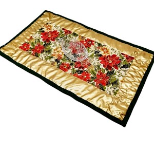 Könnte beinhalten: Ein goldfarbener und grüner gesteppter Tischläufer mit einem roten Weihnachtsstern-Blütenmuster. Der Läufer hat einen schwarzen Rand und ist mit einer durchsichtigen Glasschale verziert.