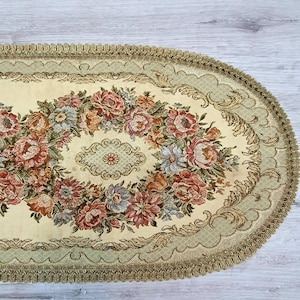 Könnte beinhalten: Ovaler Tischläufer mit einem floralen Design in Rosa-, Rot- und Blautönen. Der Läufer hat einen goldenen Rand und einen beigefarbenen Hintergrund.