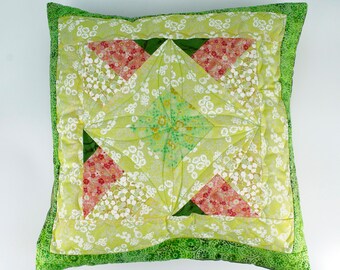 Può includere: Un cuscino con motivo verde e bianco con un design geometrico al centro. Il cuscino ha un bordo verde e un retro con motivo verde e bianco.