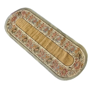 Könnte beinhalten: Ein beiger ovaler Tischläufer mit einem floralen Muster an der Kante. Der Läufer hat einen Fransenrand und eine braune Mitte.