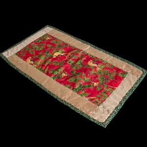 Könnte beinhalten: Ein roter und grüner Tischläufer mit einem Muster aus Vögeln und Stechpalmenbeeren. Der Läufer hat einen goldenen Rand und einen grünen Rand.