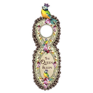 May include: A decorative door hanger with a gold and black lace design. The hanger features a bluebird with a crown, flowers, and the text "The Queen Sleeps".