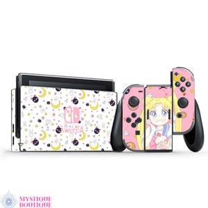 Może przedstawiać: Skórka na konsolę Nintendo Switch w kolorze różowym i białym z motywem postaci z Sailor Moon. Skórka zawiera wzór gwiazd, księżyców i kotów. Konsola jest pokazana z dwoma kontrolerami, jeden z motywem postaci z Sailor Moon, a drugi z wzorem gwiazd, księżyców i kotów.