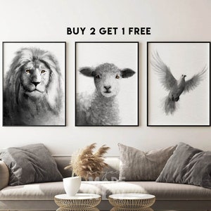 Op de afbeelding: Drie zwart-witte wandkunstprints met een leeuw, een lam en een duif. De prints zijn zwart ingelijst en hebben een witte achtergrond. De tekst "BUY 2 GET 1 FREE" wordt boven de prints weergegeven.