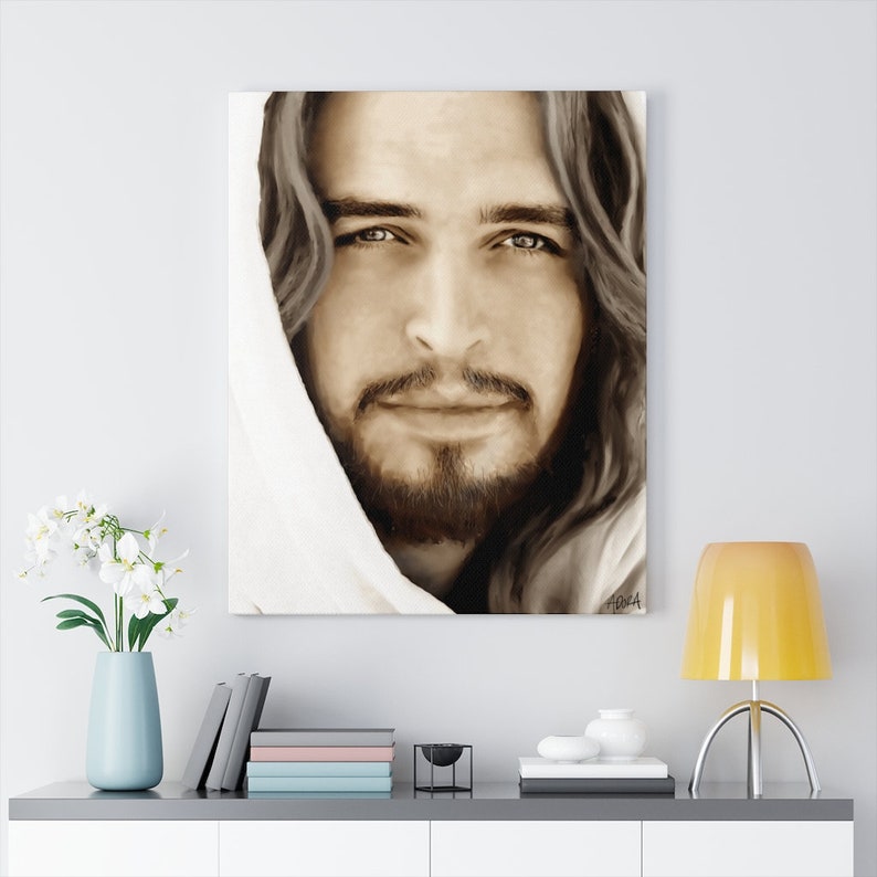 May include: A sepia-toned canvas print of a man with long brown hair and a beard. He is wearing a white robe and looking directly at the viewer. His eyes are a light brown color and he has a gentle smile.