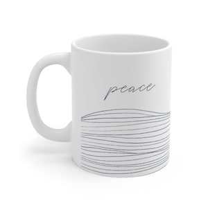 May include: White ceramic mug with a black and white abstract design and the word "peace" in cursive.